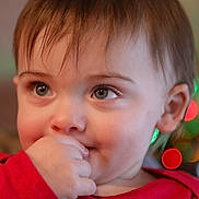 Skyler is registered to the contest to win money with this photo: baby, background_blur, bokeh, child, closeup, cute, expression, eyes, face, festive_lights, hair, hand, indoor, person, portrait, red_clothing, sitting, skin, toddler, young