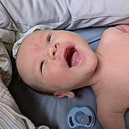 Charlie joined the competition — help win amazing prizes! baby, infant, face, mouth_open, lying_down, blanket, pacifier, skin, head, expression, cute, newborn, sleeping_area, soft_texture, child, portrait, indoors, closeup, resting, comfort