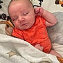 baby, newborn, sleeping, orange_onesie, blanket, animal_pattern, cozy, infant, cute, peaceful, soft_texture, closeup, portrait, resting, child, human, skin, head, hand, indoors