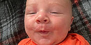 Gary joined the competition — help win amazing prizes! baby, child, closeup, cozy, cute, expression, face, head, indoors, infant, lying_down, orange_shirt, person, plaid_blanket, portrait, puckered_lips, skin, sleepy, soft_texture, young