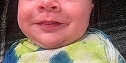 Gary is registered to the contest to win money with this photo: baby, smiling, face, infant, tie_dye, onesie, clothing, child, cute, happy, skin, portrait, person, lying_down, head, young, human, expression, joy, indoors