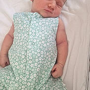 Léna a rejoint le concours — aidez-le/la à gagner de superbes lots ! baby, sleeping, infant, romper, headband, floral_pattern, white_blanket, soft_fabric, newborn, peaceful, cute, child, resting, indoors, sock, small_hands, small_feet, portrait, closeup, skin