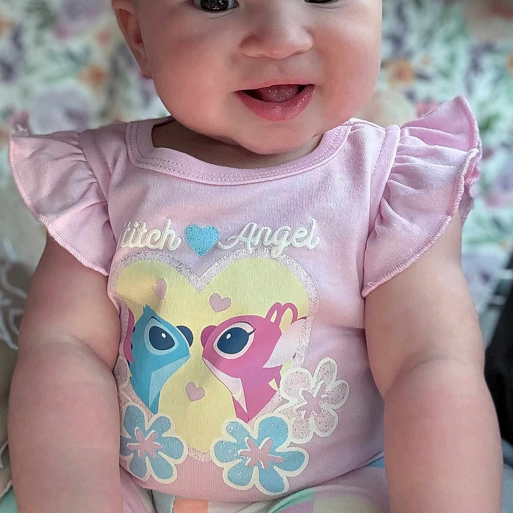 Karizmah joined the competition — help win amazing prizes! arms, baby, child, clothing, cute, cute_expression, face, floral_background, hands, happy, indoor, infant, pastel_colors, patterned_pants, pink_shirt, portrait, sitting, smiling, soft_light, young_child