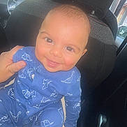 Hamid participe au concours pour gagner de l'argent avec cette photo : baby, blue_clothing, car_interior, car_seat, child, cute, daylight, dinosaur_onesie, face, hand, happy, head, indoors, infant, person, seat, smiling, supporting_hand, window, young_child