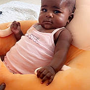 Abigael a rejoint le concours — aidez-le/la à gagner de superbes lots ! baby, infant, child, cushion, orange, pink_clothing, indoor, floor, wall, earrings, hand, face, portrait, seated, expression, soft_toy, comfort, home, person, furniture