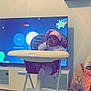 Abigael a rejoint le concours — aidez-le/la à gagner de superbes lots ! baby, high_chair, indoor, television, clock, child, purple_bonnet, floor, furniture, screen, person, baby_clothes, toy, room, sitting, headwear, footrest, modern, living_room, childhood