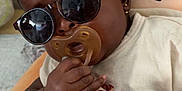 Abigael participe au concours pour gagner de l'argent avec cette photo : baby, sunglasses, pacifier, hand, pillow, acorn, earring, clothing, infant, cute, portrait, indoor, child, relaxing, soft_toy, accessory, person, face, skin, young