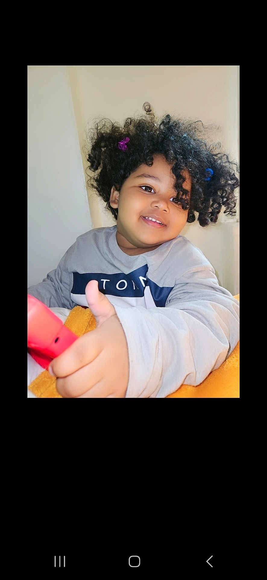 Kamaiyha joined the competition — help win amazing prizes! child, smiling, curly_hair, thumbs_up, blanket, indoor, portrait, happy, person, clothing, hair_accessory, cute, young, casual, face, hand, red_object, cozy, positive_gesture, home