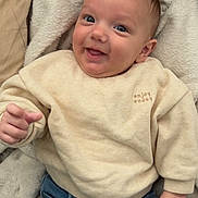 Eli a rejoint le concours — aidez-le/la à gagner de superbes lots ! baby, child, smiling, face, sweater, jeans, blanket, hand, person, portrait, cute, infant, happy, indoor, clothing, cozy, skin, head, eyes, furniture