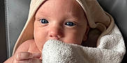 Eli a rejoint le concours — aidez-le/la à gagner de superbes lots ! baby, towel, hood, blue_eyes, close_up, face, skin, hand, infant, cute, soft, blanket, texture, cozy, portrait, looking, wrapped, child, newborn, indoor