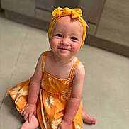 Alhya participe au concours pour gagner de l'argent avec cette photo : baby, background, barefoot, bow, child, clothing, cute, floor, happy, headband, indoor, kitchen, orange_dress, person, portrait, sitting, skin, smiling, toddler, young_child