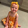baby, background, barefoot, bow, child, clothing, cute, floor, happy, headband, indoor, kitchen, orange_dress, person, portrait, sitting, skin, smiling, toddler, young_child