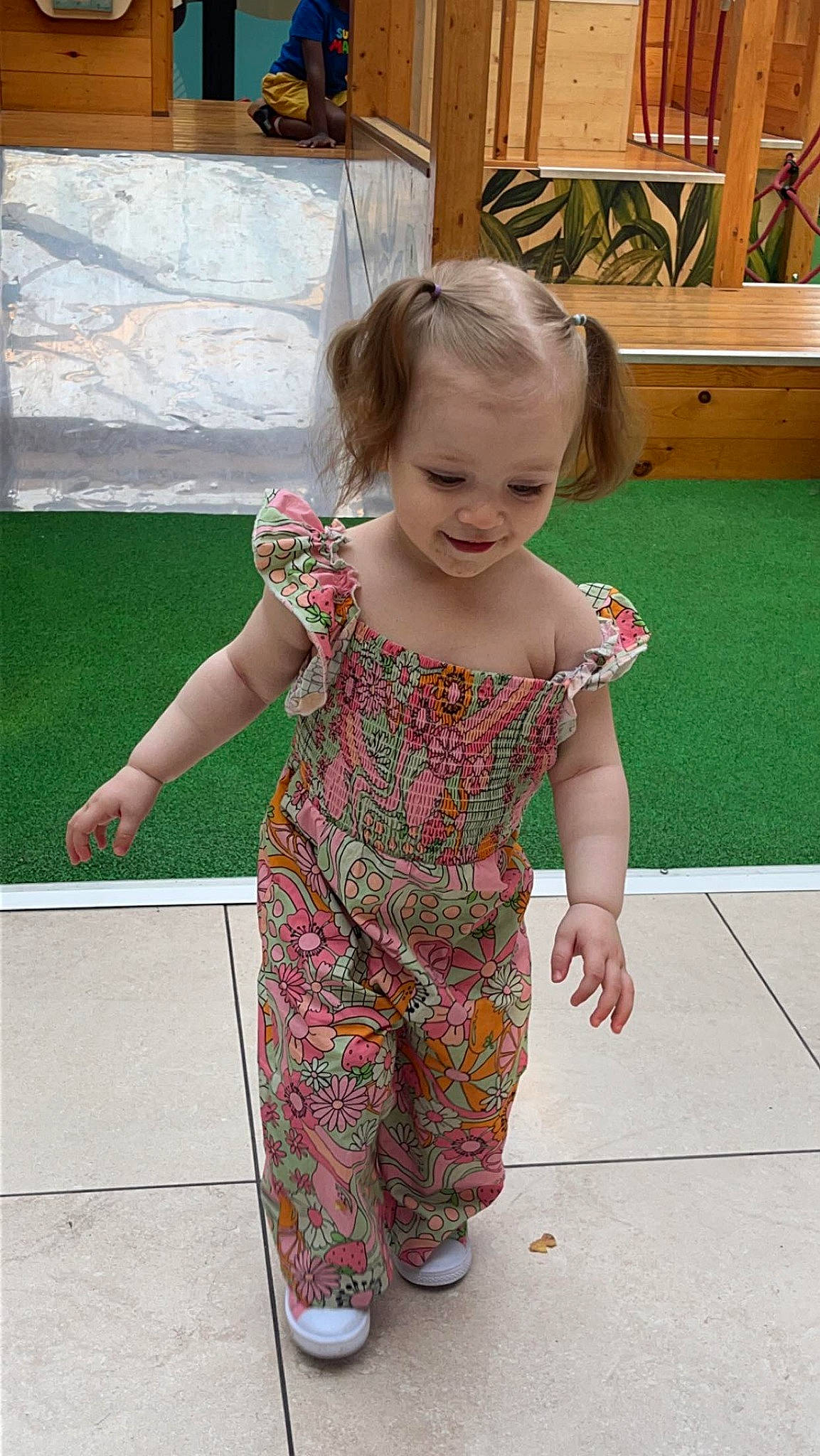 Lilya a rejoint le concours — aidez-le/la à gagner de superbes lots ! baby_toddler_clothing, barefoot, child, clothing, flooring, foot, fun, grass, hair, happy, houseplant, human_leg, joint, pattern, person, pink, sleeve, smile, toddler, vacation