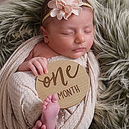 Isla joined the competition — help win amazing prizes! baby, infant, newborn, sleeping, blanket, headband, flower, wooden_sign, one_month, feet, hand, cozy, soft_texture, fur_rug, wrapped, portrait, cute, peaceful, resting, indoors