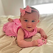 Aria joined the competition — help win amazing prizes! baby, child, pink_bow, headband, pink_dress, toy, heart_shaped_toy, blanket, bed, infant, cute, smiling, portrait, indoors, soft_light, close_up, person, skin, face, happy