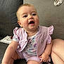 baby, child, infant, sitting, couch, clothing, vest, onesie, floral_pattern, happy, smiling, skin, face, arm, leg, indoor, furniture, soft_toys, cute, young