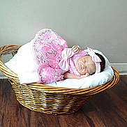 Makayla is registered to the contest to win money with this photo: baby, newborn, sleeping, basket, pink_dress, headband, indoor, wooden_floor, wicker, blanket, cozy, peaceful, infant, child, cute, portrait, resting, soft, decor, floor