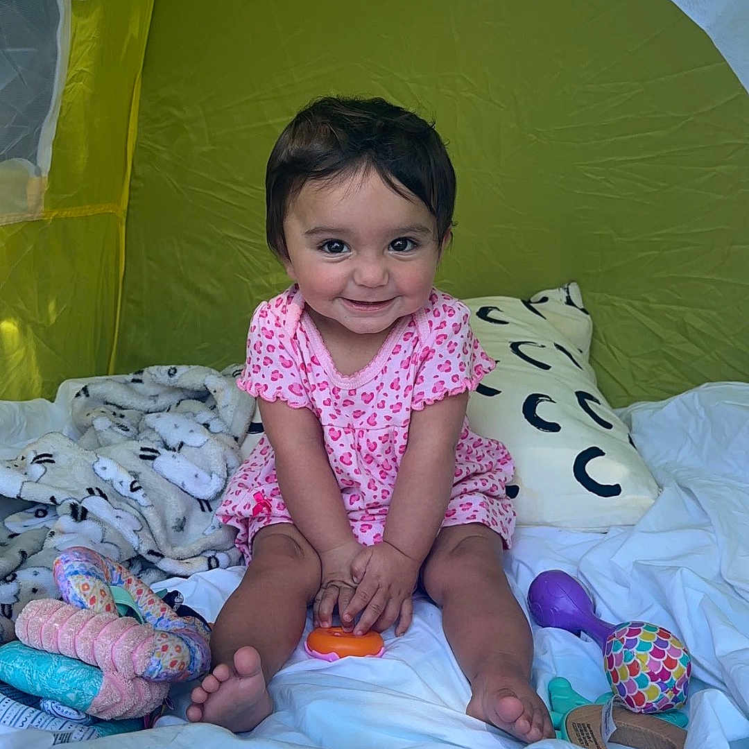 Sadie is registered to the contest to win money with this photo: architecture, baby, balloon, building, camping, clothing, cushion, dress, face, furniture, head, homedecor, outdoors, person, photography, portrait, quilt, shelter, sitting, tent