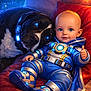 baby, dog, blue_eyes, space_suit, futuristic, cushion, red_cushion, glowing, thumbs_up, digital_art, sci_fi, robotic_elements, black_dog, white_fur, portrait, indoor, cute, childlike, fantasy, cozy