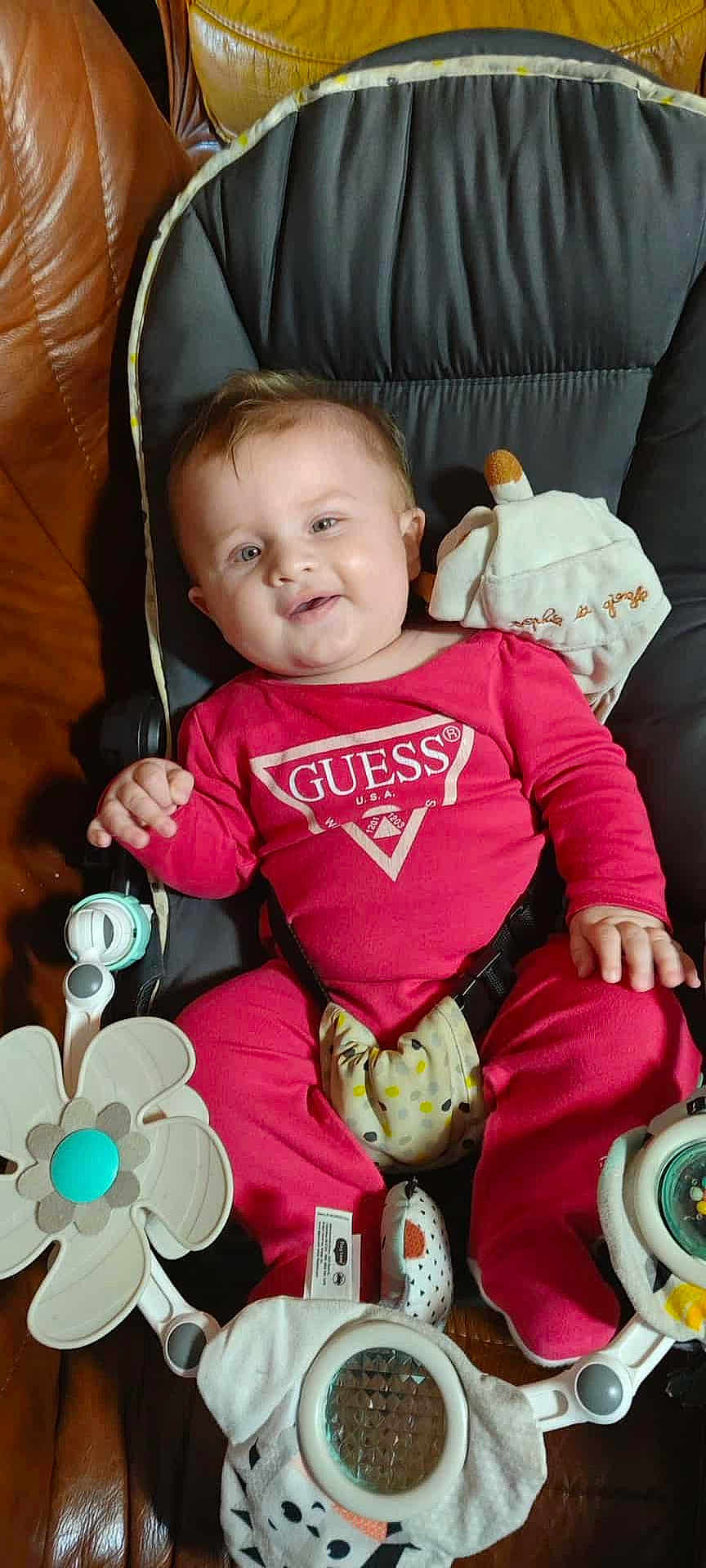 éléna a rejoint le concours — aidez-le/la à gagner de superbes lots ! baby, child, infant, red_clothing, guess_logo, smiling, seated, baby_chair, toy, colorful, indoor, happy, cute, face, hand, footwear, soft_toys, comfort, leather_chair, closeup