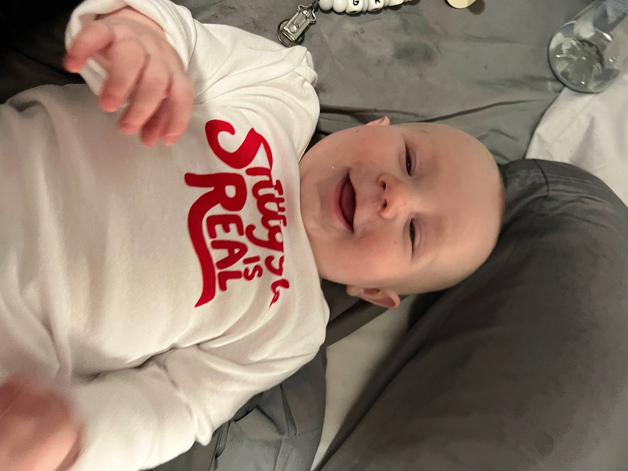 Grayson is registered to the contest to win money with this photo: baby, baby_laughing, baby_toddler_clothing, carmine, cheek, child, chin, comfort, elbow, fun, happy, mouth, person, sitting, sleeve, smile, t_shirt, toddler, top, tree
