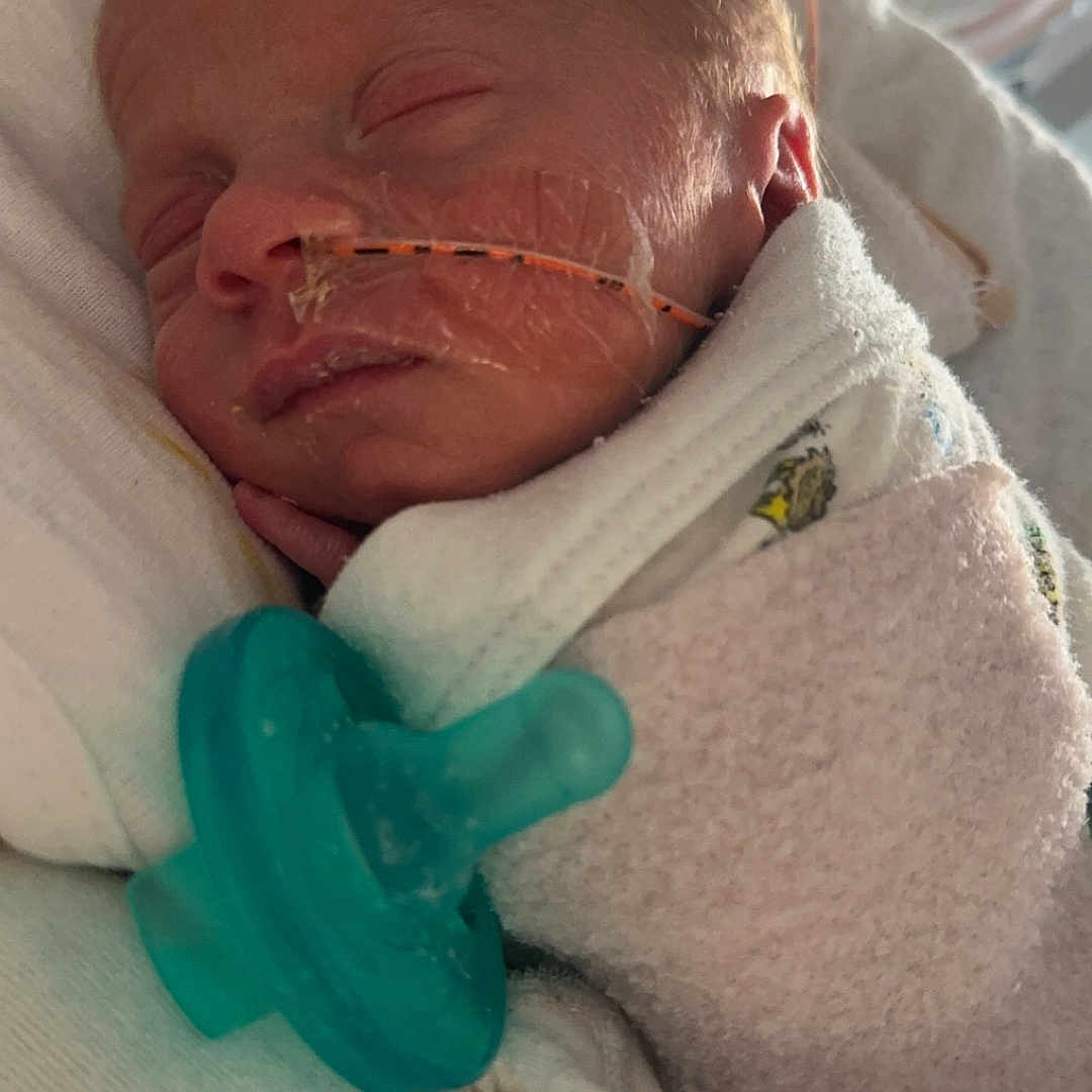 Russell is registered to the contest to win money with this photo: architecture, baby, blanket, bodypart, building, clothing, cushion, face, furniture, glove, head, homedecor, hospital, newborn, person, photography, portrait, quilt, sleeping, towel