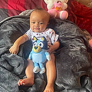 Jasmine is registered to the contest to win money with this photo: baby, child, blanket, plush_toy, stuffed_animal, hello_kitty, bed, pillow, comfort, indoor, cute, smiling, toddler, soft_texture, relaxing, cartoon_character, foot, hand, clothing, portrait