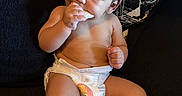 Dylan is registered to the contest to win money with this photo: baby, child, couch, cute, diaper, face, food, hand, head, indoor, infant, legs, nibbling, pattern, person, pillow, relaxing, snack, socks, towel