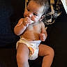 baby, child, couch, cute, diaper, face, food, hand, head, indoor, infant, legs, nibbling, pattern, person, pillow, relaxing, snack, socks, towel