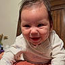 Dylan is registered to the contest to win money with this photo: baby, smiling, infant, hand, indoor, wooden_blinds, person, clothing, dimple, face, happy, adult_hand, bedroom, furniture, cute, young_child, long_sleeve, skin, head, expression