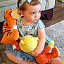 Kloe joined the competition — help win amazing prizes! toddler, child, plush_toy, stuffed_animal, blue_bow, dress, carpet, floor, sofa, indoor, child_sitting, curious_expression, toy, orange, yellow, person, cute, home, playful, young_child