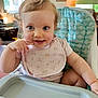baby, high_chair, bib, smiling, blue_eyes, indoor, child, curly_hair, person, cute, playful, furniture, table, skin, pink_clothing, young_child, infant, happy, portrait, home