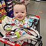 baby, shopping_cart, store, aisle, blanket, pajamas, smiling, child, indoor, retail, person, keys, lanyard, floor, shelf, product, snacks, happy, face, family_dollar