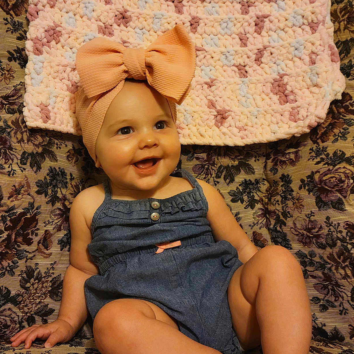 Eliana is registered to the contest to win money with this photo: baby, cap, clothing, couch, cushion, dress, face, furniture, happy, hat, head, homedecor, jeans, pants, person, photography, portrait, shorts, sitting, smile