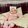 baby, infant, child, bow_headband, pink_sweater, striped_pants, socks, plaid_blanket, couch, pillow, cozy, smile, cheeks, seated, indoors, textile, portrait, home, furniture, cute