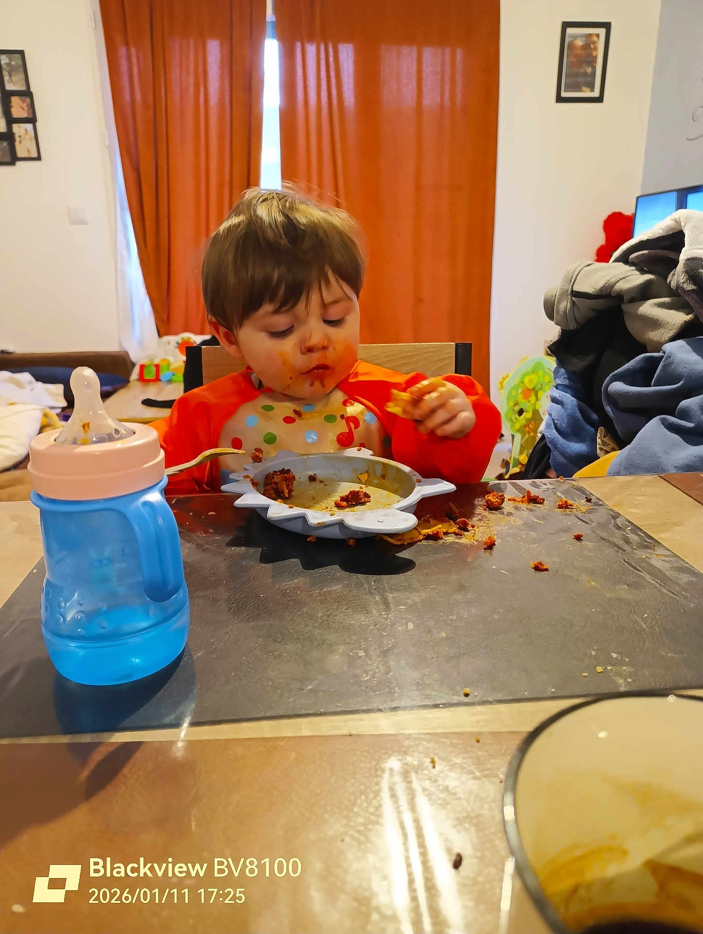Austin a rejoint le concours — aidez-le/la à gagner de superbes lots ! child, toddler, bib, food, messy_face, bowl, plate, sippy_cup, table, chair, spoon, curtains, living_room, meal, eating, food_spill, toys, clothing, highchair, timestamp