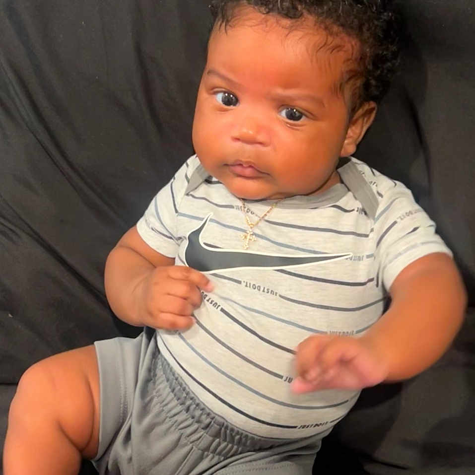 Zaylan is registered to the contest to win money with this photo: baby, black_cushion, child, couch, cross_pendant, curly_hair, expression, eyes, face, feet, gold_necklace, hands, indoors, infant, legs, nike_logo, portrait, shorts, skin, striped_shirt
