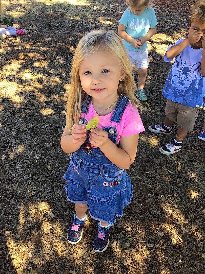 Scarlett is registered to the contest to win money with this photo: botany, eye, facial_expression, footwear, gesture, grass, hairstyle, happy, head, joy, leaf, leisure, morning, people_in_nature, person, pink, public_space, shoe, smile, sneakers
