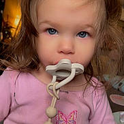 Mötley joined the competition — help win amazing prizes! baby, beaded_clip, blue_eyes, butterfly_patch, casual_clothing, child, closeup, cute, expression, face, hair, indoor, pacifier, person, pink_shirt, portrait, sitting, toddler, toy, young_child