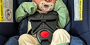 Arlo joined the competition — help win amazing prizes! baby, infant, car_seat, pacifier, clothing, green_hat, mittens, footwear, blue_cushion, seatbelt, safety_harness, newborn, cute, indoors, portrait, expression, tiny_feet, fabric, warning_label, child