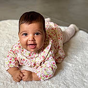 Charlie a rejoint le concours — aidez-le/la à gagner de superbes lots ! baby, infant, smiling, face, eyes, hands, floral_dress, white_rug, crawling, cute, child, portrait, indoors, soft_texture, happy, young, person, skin, head, expression