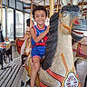 Ja'Kobe Anthony joined the competition — help win amazing prizes! child, carousel, horse, amusement_ride, indoor, smiling, curly_hair, blue_outfit, spiderman, playful, vintage, entertainment, fun, portrait, happy, riding, toy_horse, light_bulbs, background, person