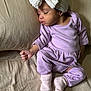 Adaly is registered to the contest to win money with this photo: baby, sleeping, headband, bow, purple_outfit, socks, couch, pillow, bed, infant, child, rest, soft_fabric, indoors, peaceful, skin, hand, footwear, clothing, portrait