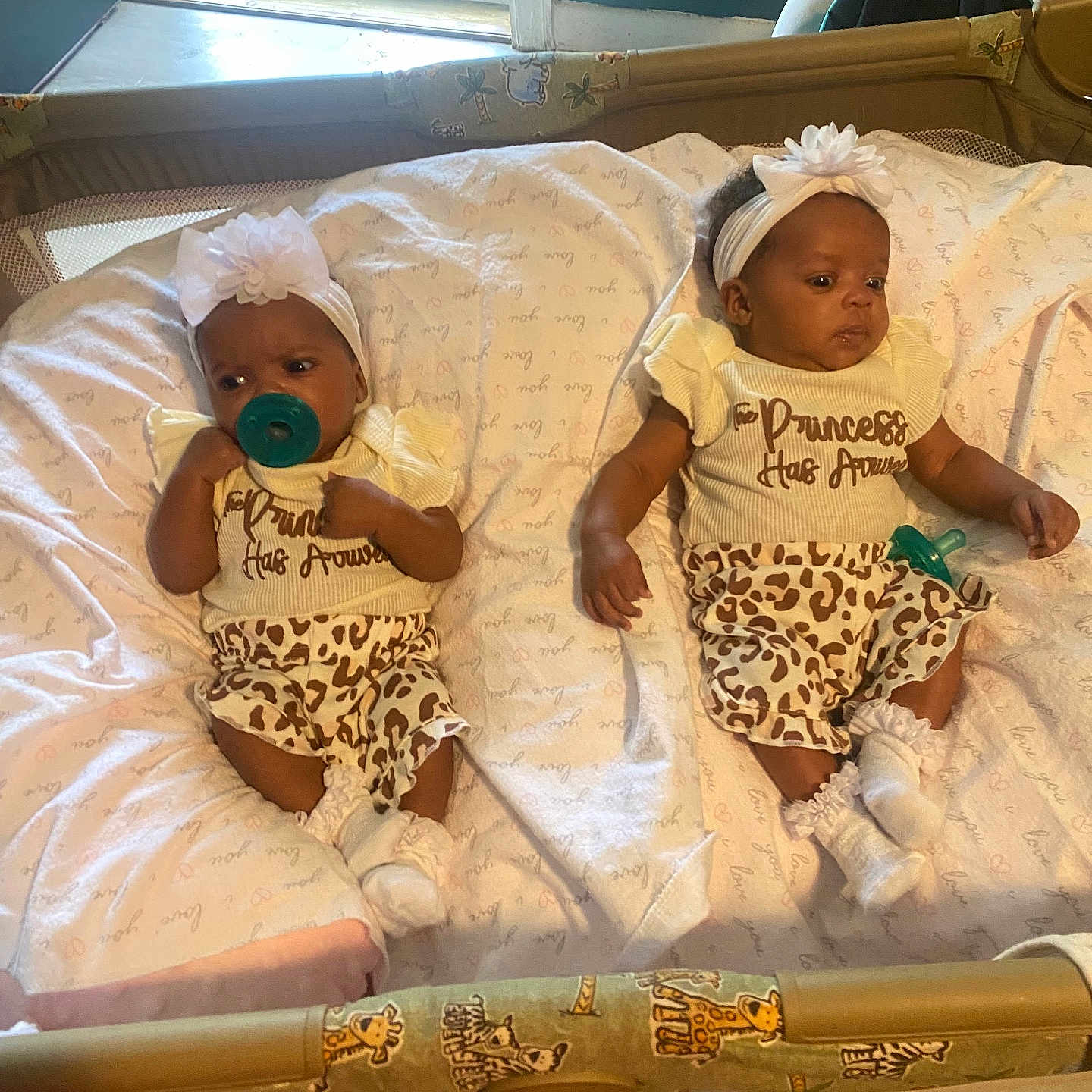 Londyn And Jordyn is registered to the contest to win money with this photo: baby, twins, infant, pacifier, headband, flower, leopard_print, clothing, blanket, playpen, indoor, window, sock, cute, child, person, resting, toddler, matching_outfits, nursery