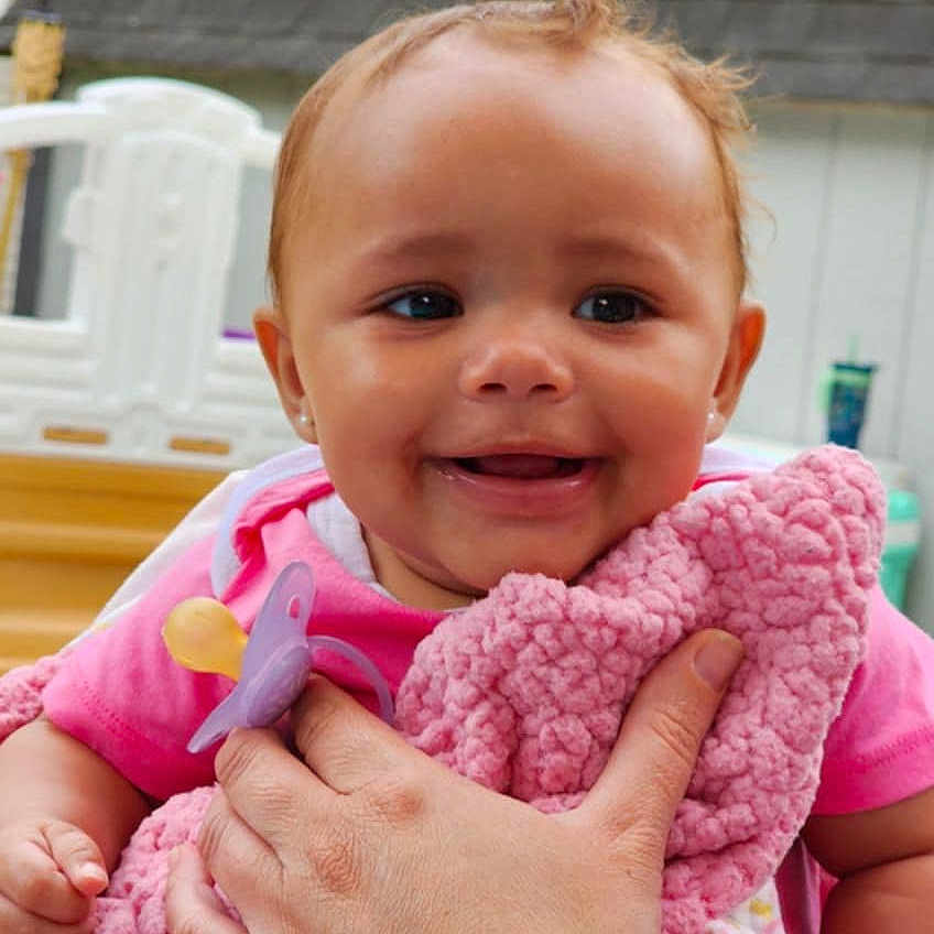 Aziylah is registered to the contest to win money with this photo: baby, blanket, child, clothing, cute, expression, face, hand, happy, holding, infant, outdoor, pacifier, person, pink_blanket, portrait, skin, smiling, warm, young