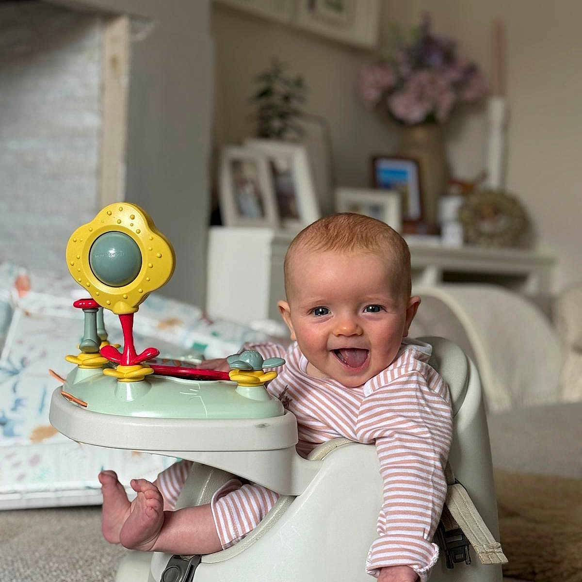 Brea is registered to the contest to win money with this photo: baby, baby_seat, carpet, child, decor, face, foot, furniture, hand, happy, indoor, infant, living_room, person, photography, play, smile, striped_clothing, tongue_out, toy