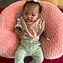 Cimani joined the competition — help win amazing prizes! baby, infant, pink_bib, pink_cushion, curly_hair, green_pants, pacifier, red_blanket, couch, carpet, indoor, child, cute, comfortable, clothing, person, face, head, relaxed, small_hand