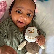 Alya a rejoint le concours — aidez-le/la à gagner de superbes lots ! baby, baby_clothing, child, closeup, cozy, cute, face, green_sweater, hand, happy, indoors, infant, lying_down, person, pink_cap, plush_monkey, portrait, smiling, soft_toy, toy