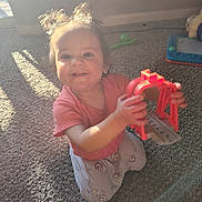 Delanie is registered to the contest to win money with this photo: toddler, child, toy, red_toy, carpet, sunlight, indoor, pigtails, smiling, kneeling, playtime, happy, cute, casual_clothing, home, person, young_child, bright, shadow, fun