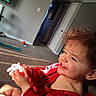 Delanie is registered to the contest to win money with this photo: toddler, child, smile, curly_hair, red_clothing, indoor, carpet, television, toy, light, happy, person, face, hand, sitting, home, play, young_child, bright, cute